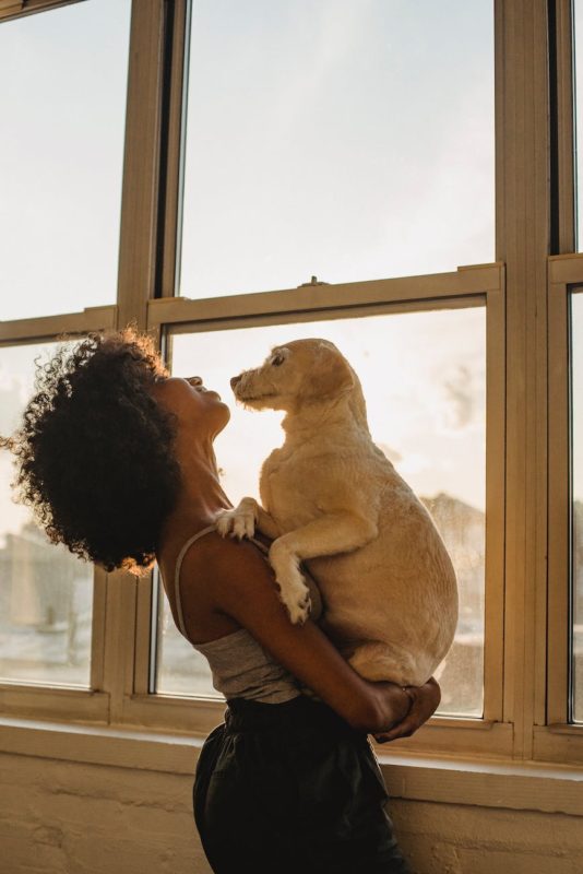 black woman with dog near window